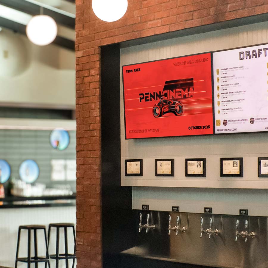 A TV screen in the lobby at Penn Cinema showcasing a stylized adaption of the logo for the film Tron: Ares.